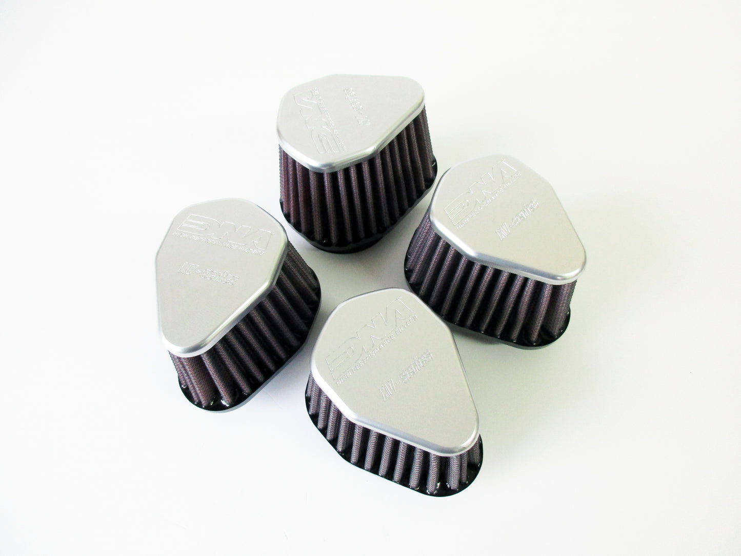 Four grey metal topped universal air filters, with pleated media, arranged in a loose square on a plain white background.