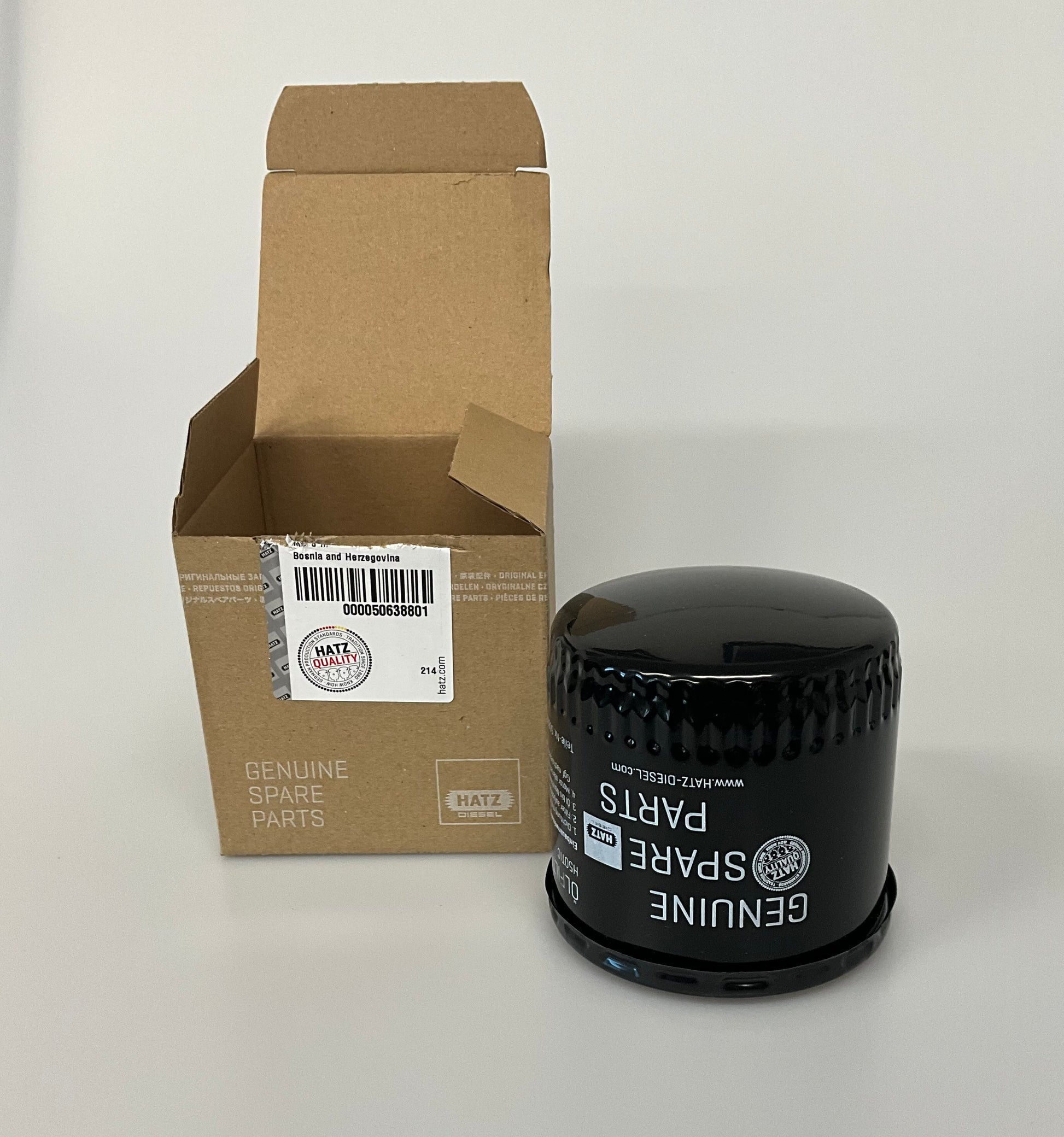 A black genuine hatz oil filter with white text, next to its brown cardboard packaging box, labelled as Hatz Spare Parts.