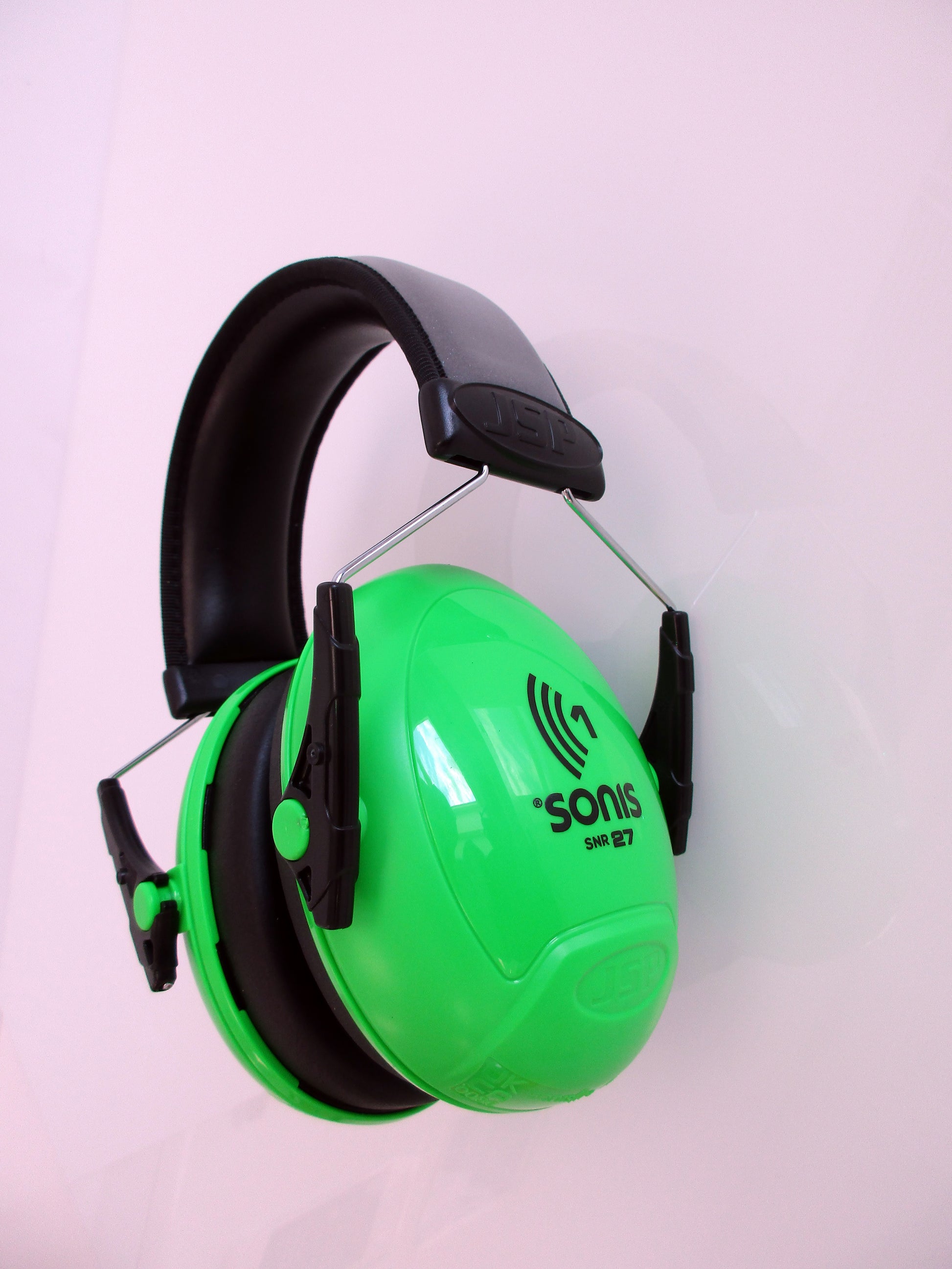Green and black over-ear hearing protection earmuffs with a visible 'sonis' logo, shown against a plain light pink background.