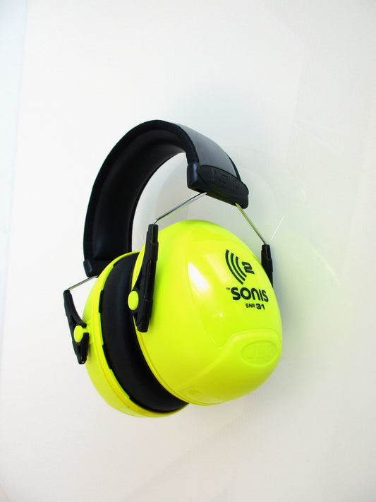 A pair of bright neon yellow and black Sonis earmuffs hanging against a plain white wall.
