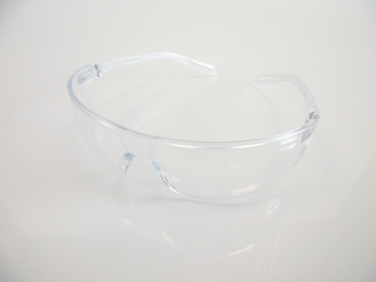 Clear plastic safety glasses, with transparent lenses, shown on a plain white background.