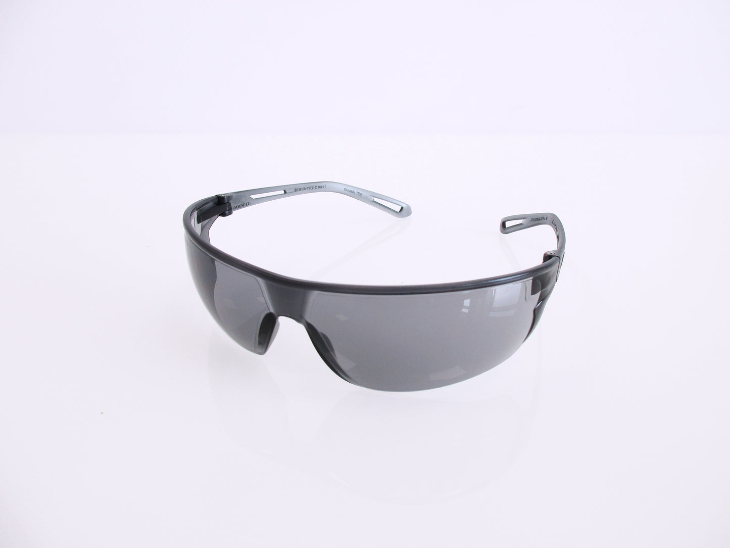 Shield-style safety glasses with a dark gray translucent frame and tinted lenses, photographed on a clean white background.