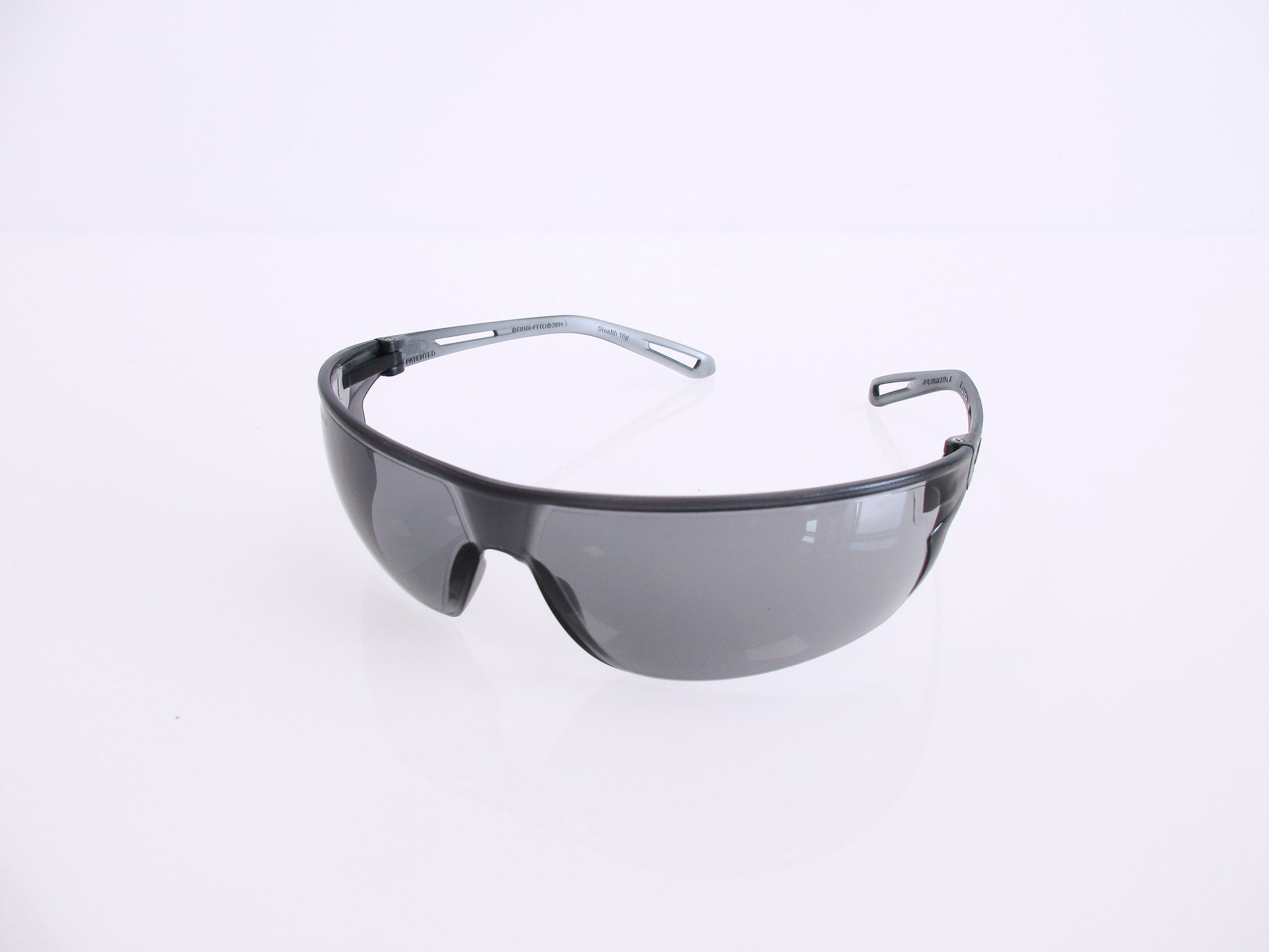 Shield-style safety glasses with a dark gray translucent frame and tinted lenses, photographed on a clean white background.