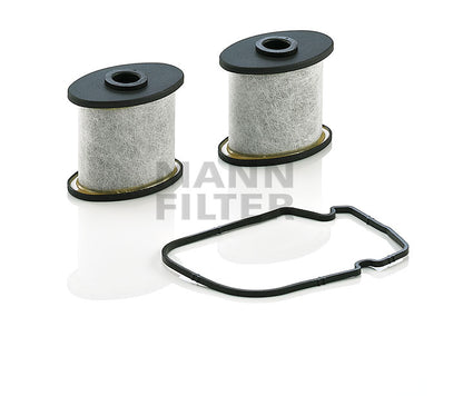 Two cylindrical ventilators, with black tops and bottoms, shown alongside a black rubber gasket on a white reflective background. A semi-transparent 'MANN FILTER' logo watermark is visible in the centre.