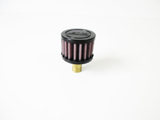 A small cylindrical crank case vent with a black top cap, red pleated media, and a brass-coloured bottom fitting, photographed on a plain white background.