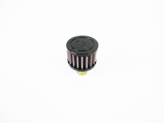 A small cylindrical crank case vent with a black top cap, red pleated media, and a brass-coloured bottom fitting, photographed on a plain white background.