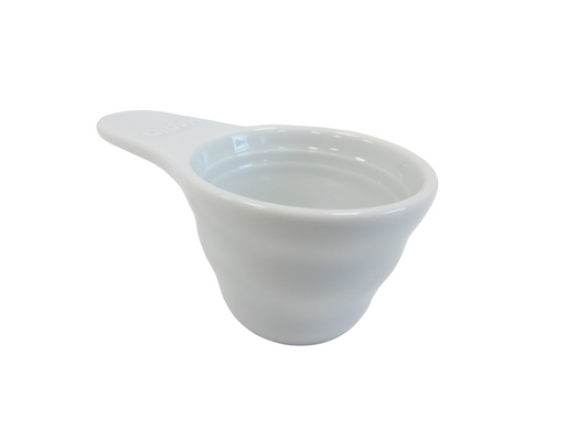 A white ceramic measuring scoop with a handle, shown from a three-quarters angle on a solid white background.