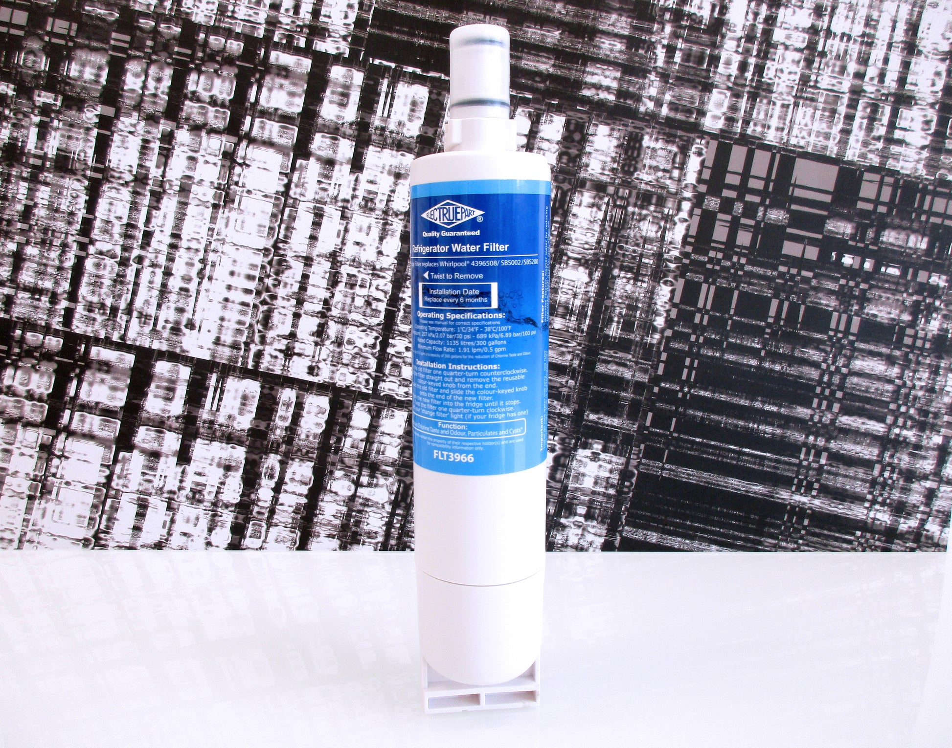 A single white cylindrical water filter, with a blue label displaying part number FLT3966, standing upright on a small clear top against a black-and-white patterned backdrop.