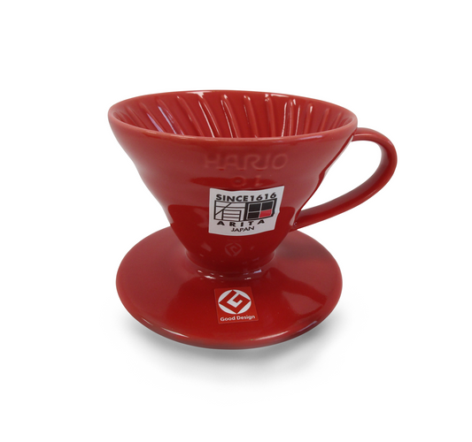 A red ceramic pour-over coffee dripper, featuring the Hario V60 logo and a white brand sticker on the front, set against a plain white background.