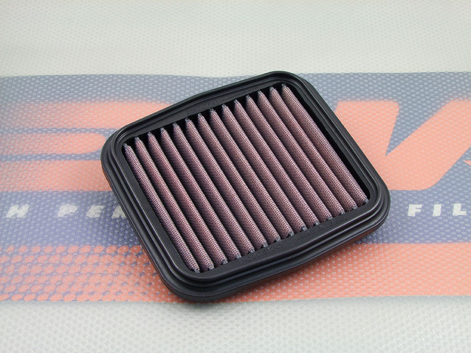 A square motorcycle air filter, with pleated filter media and a black PU frame, resting on a branded orange and blue filter mat.