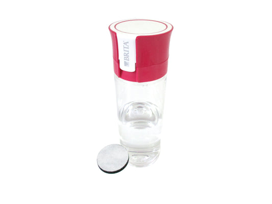A BRITA water filter bottle with a clear plastic body, a bright pink top cap, and a separate circular black-and-white filter element placed beside it on a white background.