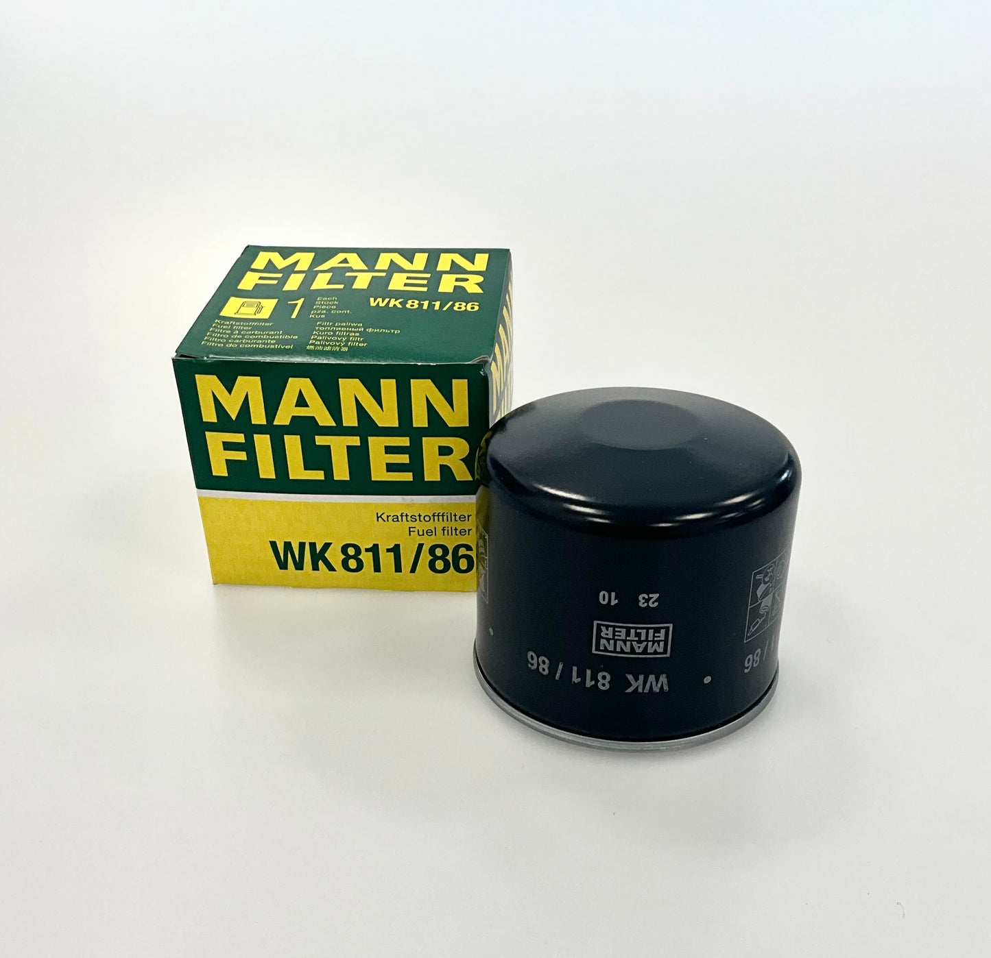 A Mann Filter WK 811/86 oil filter, next to its original green and yellow retail box , shown on a clean white background.