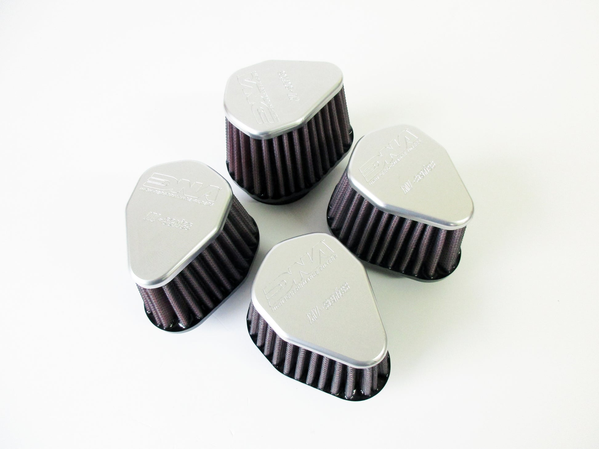 Four grey metal topped universal air filters, with pleated media, arranged in a loose square on a plain white background.